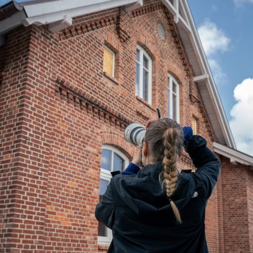 Frau macht Foto von Backstein-Haus